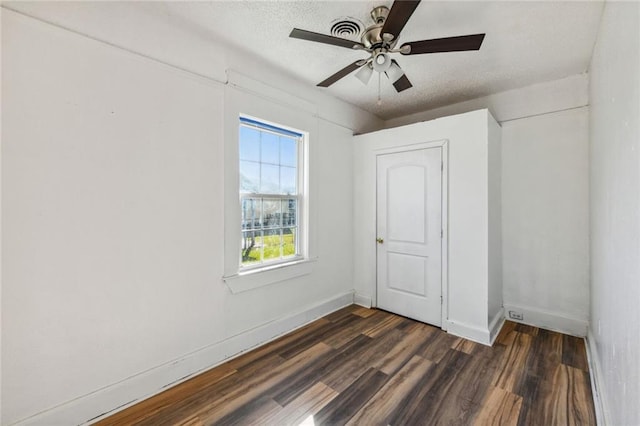 unfurnished bedroom with ceiling fan, a textured ceiling, and dark hardwood / wood-style floors