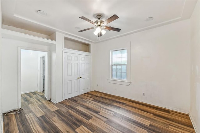 unfurnished bedroom with a closet, ceiling fan, and dark hardwood / wood-style flooring