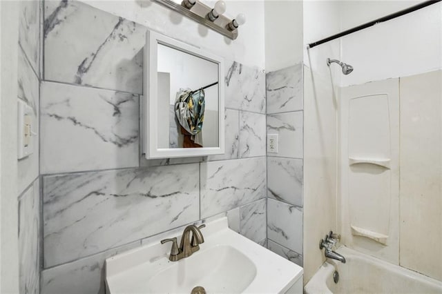 bathroom with tile walls, vanity, and tiled shower / bath