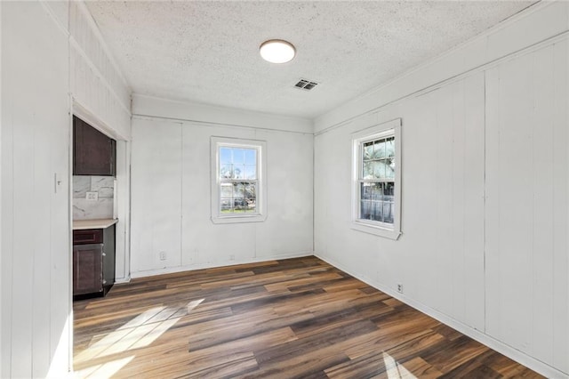 unfurnished room featuring wood walls, a textured ceiling, and dark hardwood / wood-style flooring