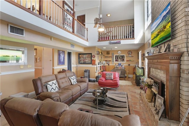 tiled living room with a high ceiling, a brick fireplace, and ceiling fan