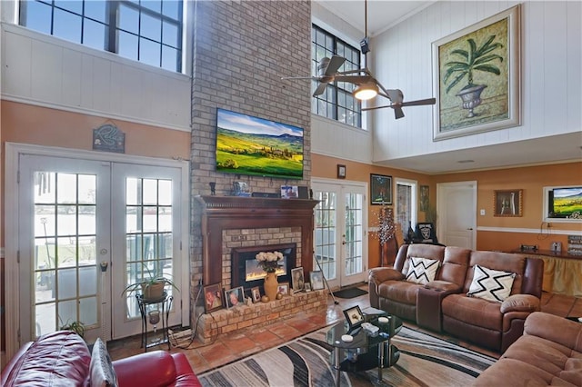 tiled living room featuring a fireplace, french doors, ceiling fan, and a high ceiling