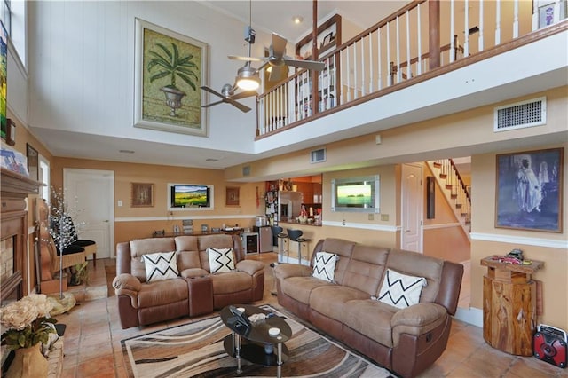 tiled living room with ceiling fan and a high ceiling