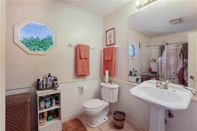 bathroom with tile patterned floors, toilet, sink, wood walls, and curtained shower