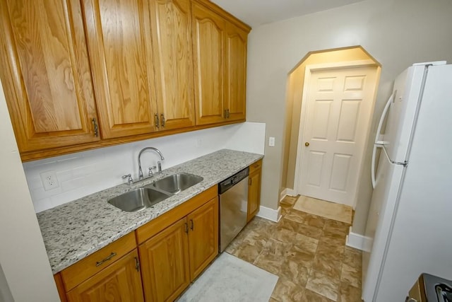 kitchen with decorative backsplash, light stone counters, sink, dishwasher, and white fridge