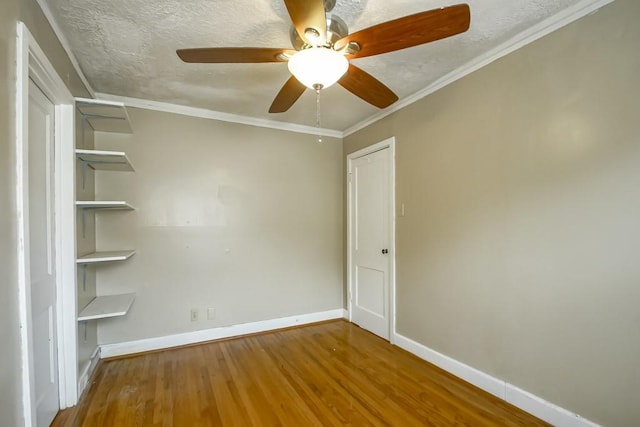 spare room featuring ceiling fan, wood-type flooring, a textured ceiling, and ornamental molding