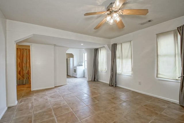 tiled empty room featuring ceiling fan and washer and dryer