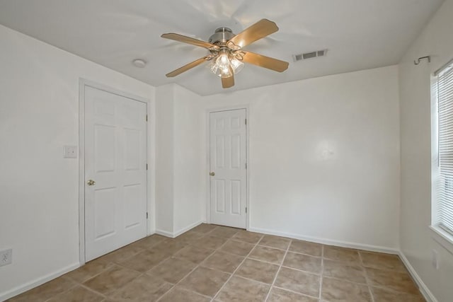 tiled empty room featuring ceiling fan