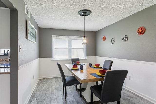 dining area with sink, hardwood / wood-style flooring, and a textured ceiling