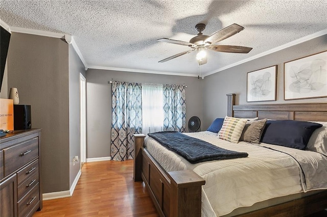 bedroom featuring ceiling fan, ornamental molding, hardwood / wood-style floors, and a textured ceiling