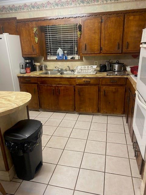 kitchen featuring white refrigerator, sink, and light tile patterned floors