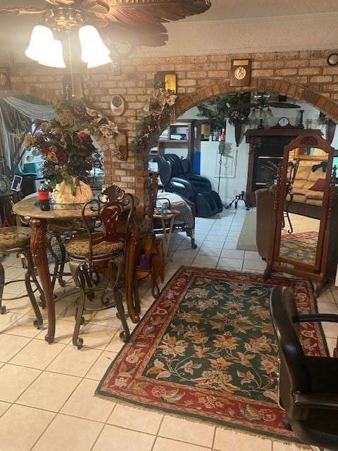 dining space with tile patterned flooring, brick wall, and ceiling fan