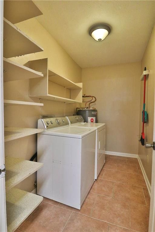 washroom with water heater, separate washer and dryer, and light tile patterned floors