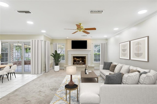 tiled living room featuring crown molding, a fireplace, and ceiling fan