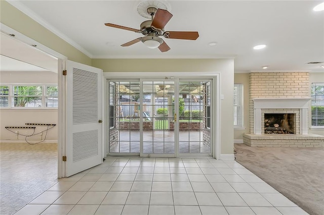 interior space featuring a brick fireplace, ceiling fan, light colored carpet, and plenty of natural light