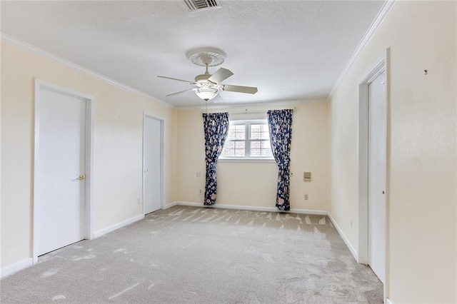 spare room with ceiling fan, light colored carpet, and crown molding