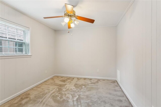 empty room with ceiling fan, light colored carpet, and crown molding