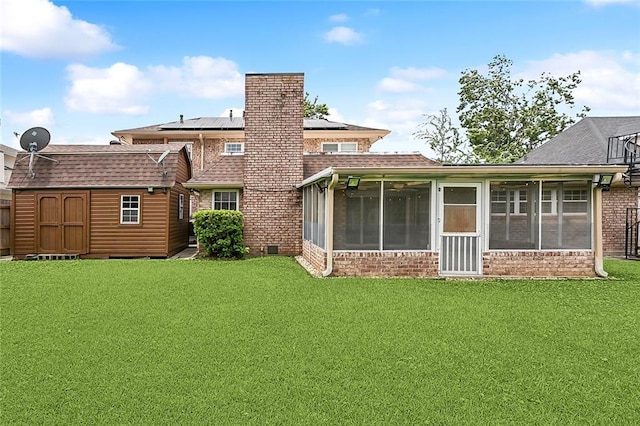 back of property featuring a sunroom, a yard, and a storage unit