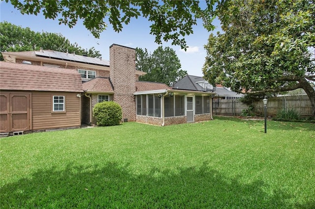 back of house with a sunroom, a storage shed, and a yard