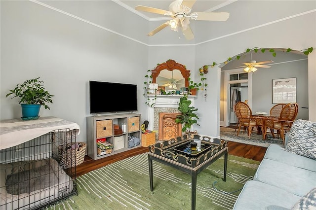 living room featuring wood finished floors, ornamental molding, a fireplace, and ceiling fan