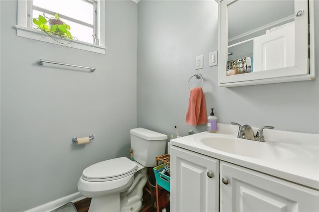 half bath with toilet, vanity, and baseboards