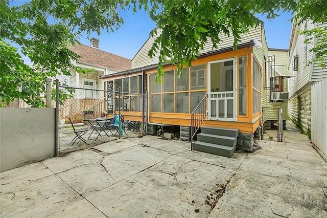 view of patio / terrace featuring a gate, cooling unit, fence, and a sunroom