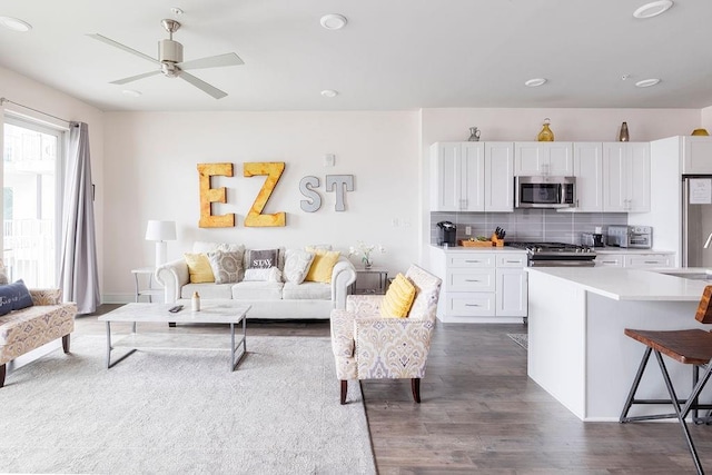 living room with sink, ceiling fan, and dark wood-type flooring