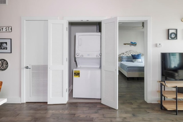 clothes washing area featuring dark hardwood / wood-style flooring, stacked washer / drying machine, and ceiling fan