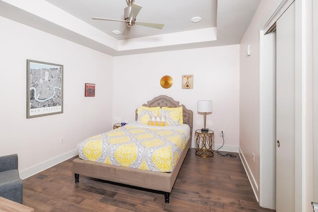 bedroom featuring a closet, ceiling fan, a raised ceiling, and dark wood-type flooring