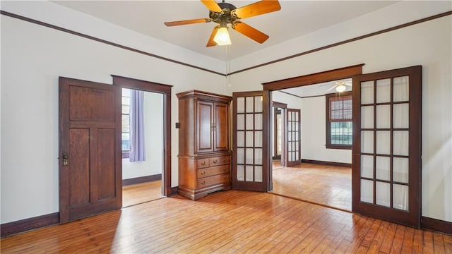 empty room with ceiling fan, light hardwood / wood-style floors, and french doors