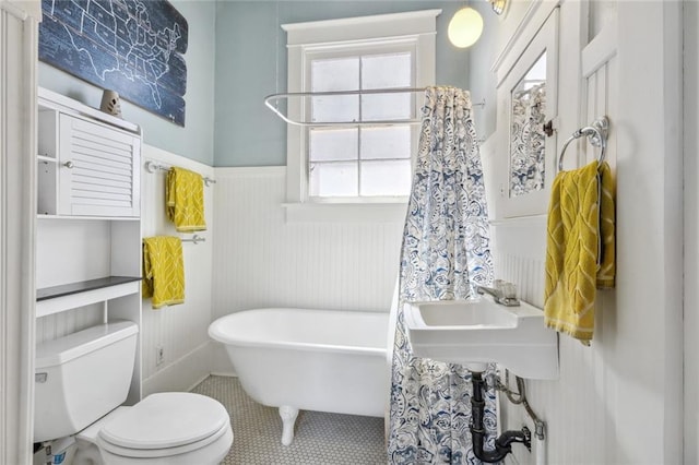 bathroom with a tub to relax in, toilet, and tile patterned flooring