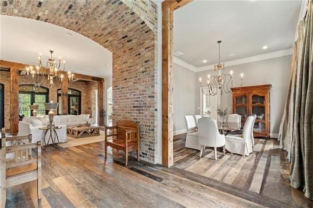 dining area featuring wood-type flooring, crown molding, and brick wall