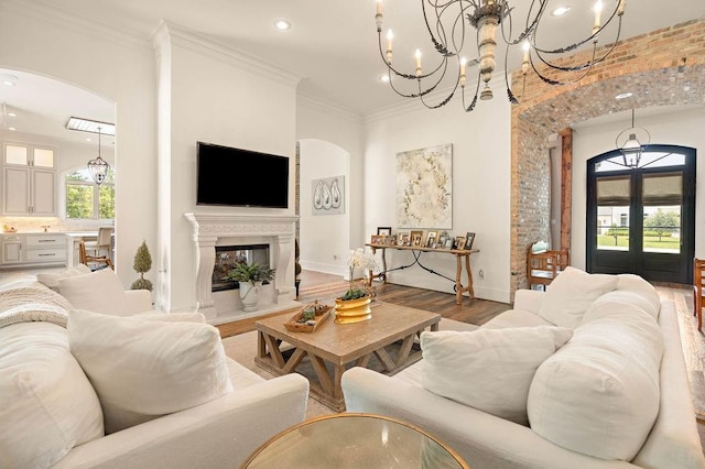 living room featuring a chandelier, french doors, ornamental molding, and hardwood / wood-style floors