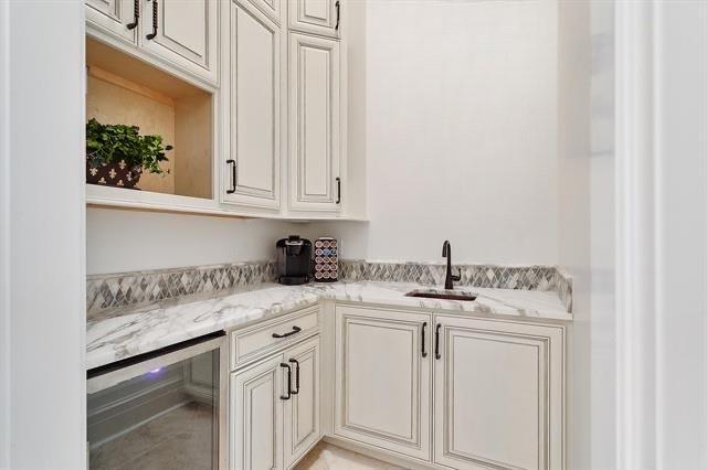 bar with light stone countertops, wine cooler, and sink