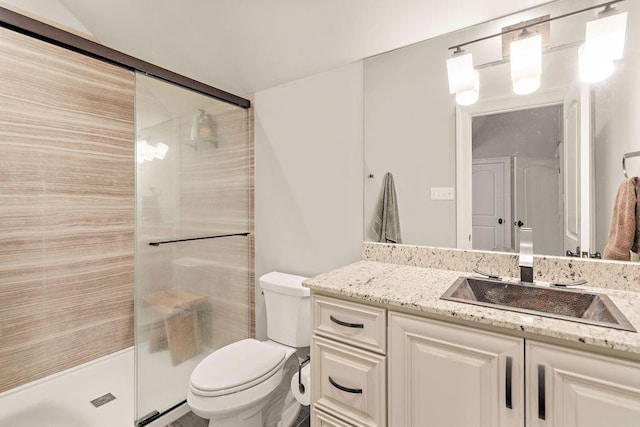 bathroom with a shower with door, vanity, and toilet