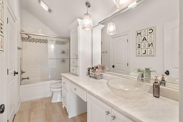 full bathroom with vanity, toilet, combined bath / shower with glass door, and vaulted ceiling