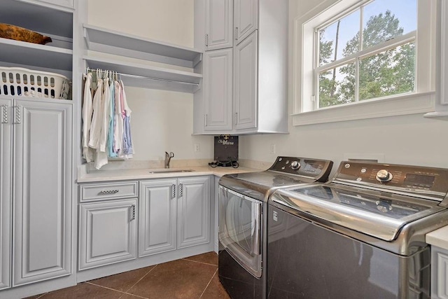 laundry room with dark tile patterned flooring, cabinets, sink, and washing machine and clothes dryer