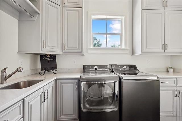 laundry room with cabinets, separate washer and dryer, and sink