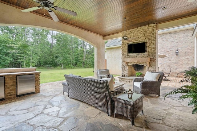 view of patio featuring an outdoor stone fireplace and ceiling fan