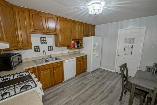 kitchen with brown cabinets, white appliances, light countertops, and a sink