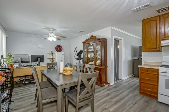 dining room featuring visible vents, baseboards, a ceiling fan, and light wood finished floors