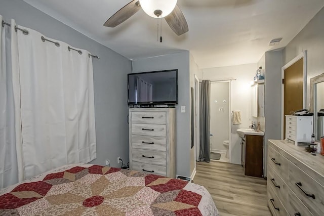 bedroom featuring ensuite bath, a ceiling fan, light wood-style floors, and a sink