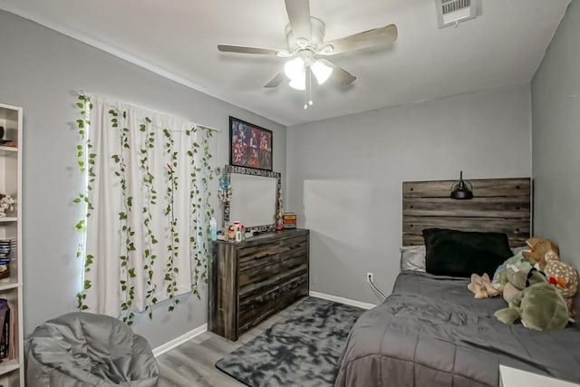 bedroom featuring a ceiling fan, wood finished floors, visible vents, and baseboards