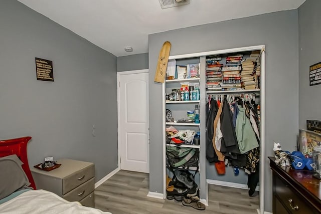 bedroom featuring wood finished floors, visible vents, a closet, and baseboards