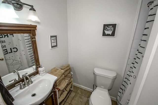 bathroom featuring toilet, a shower with shower curtain, tile patterned flooring, baseboards, and vanity