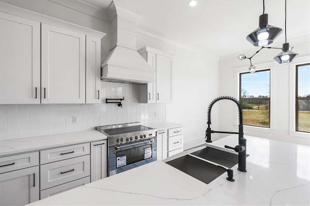 kitchen featuring white cabinetry, backsplash, high end stove, custom exhaust hood, and sink