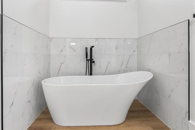 bathroom featuring hardwood / wood-style flooring and tile walls