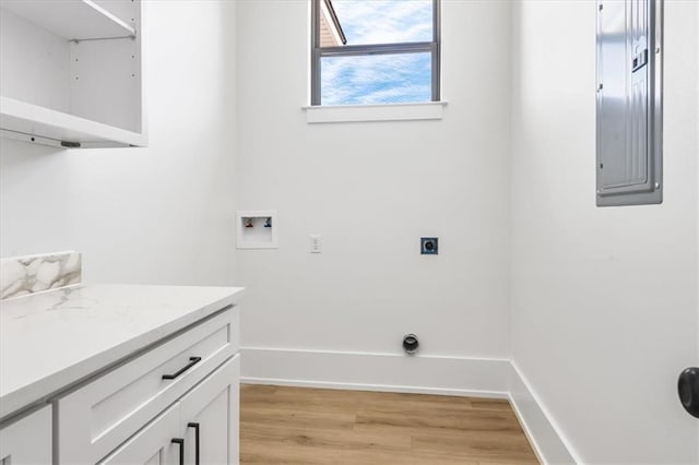 washroom featuring hookup for an electric dryer, light wood-type flooring, electric panel, washer hookup, and cabinets