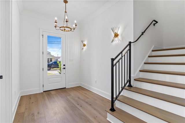 entrance foyer with ornamental molding, light hardwood / wood-style flooring, and a chandelier