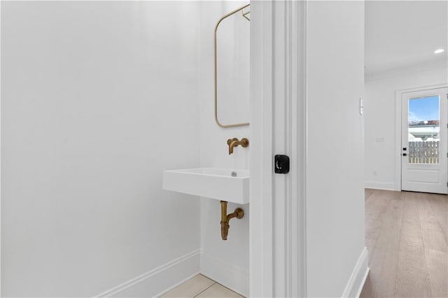 bathroom with sink, crown molding, and hardwood / wood-style flooring